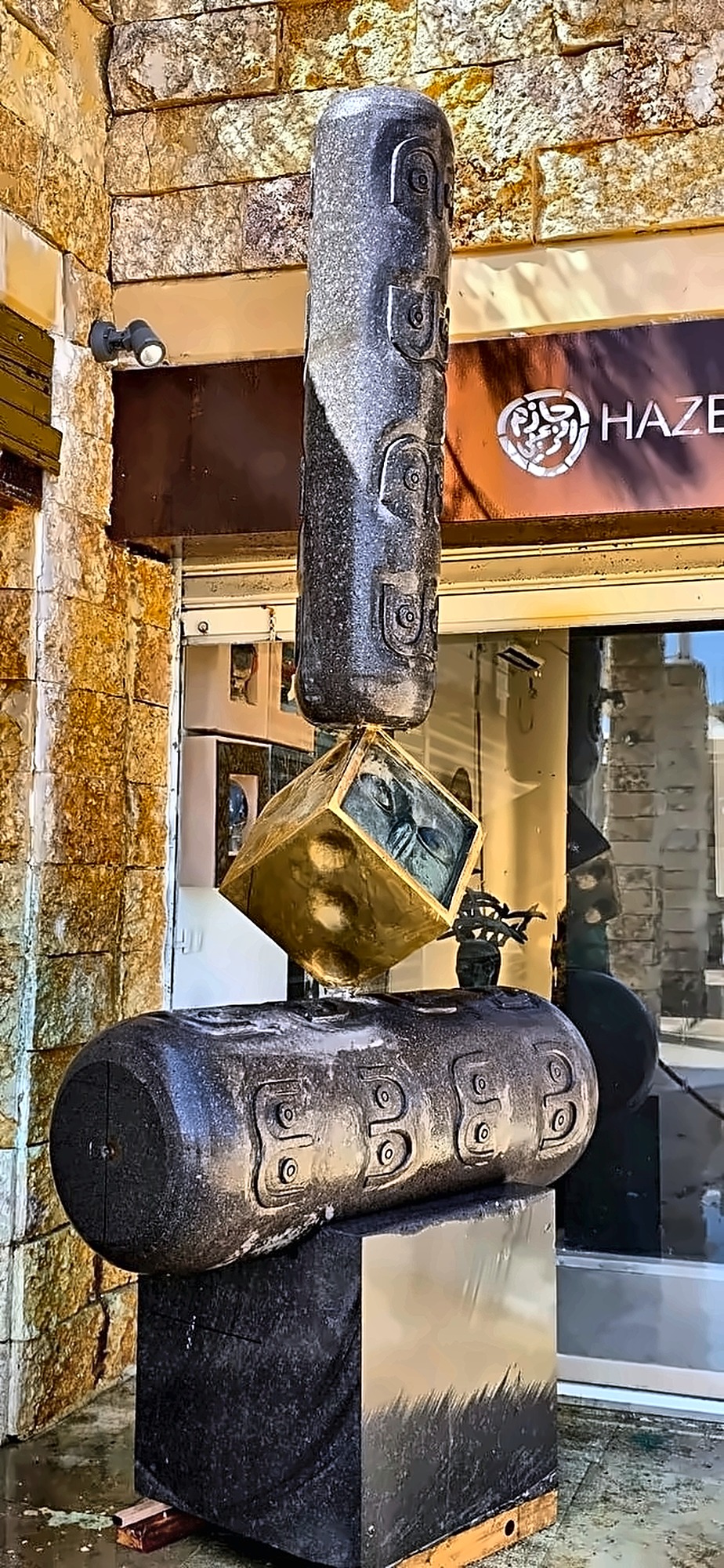 The basalt and bronze work standing outside the gallery door in daylight.