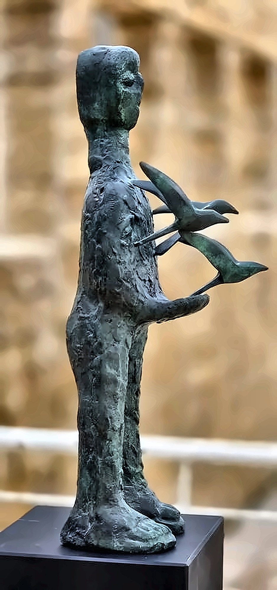 A taller, thinner version of the standing bearer, birds breaking away to one side.