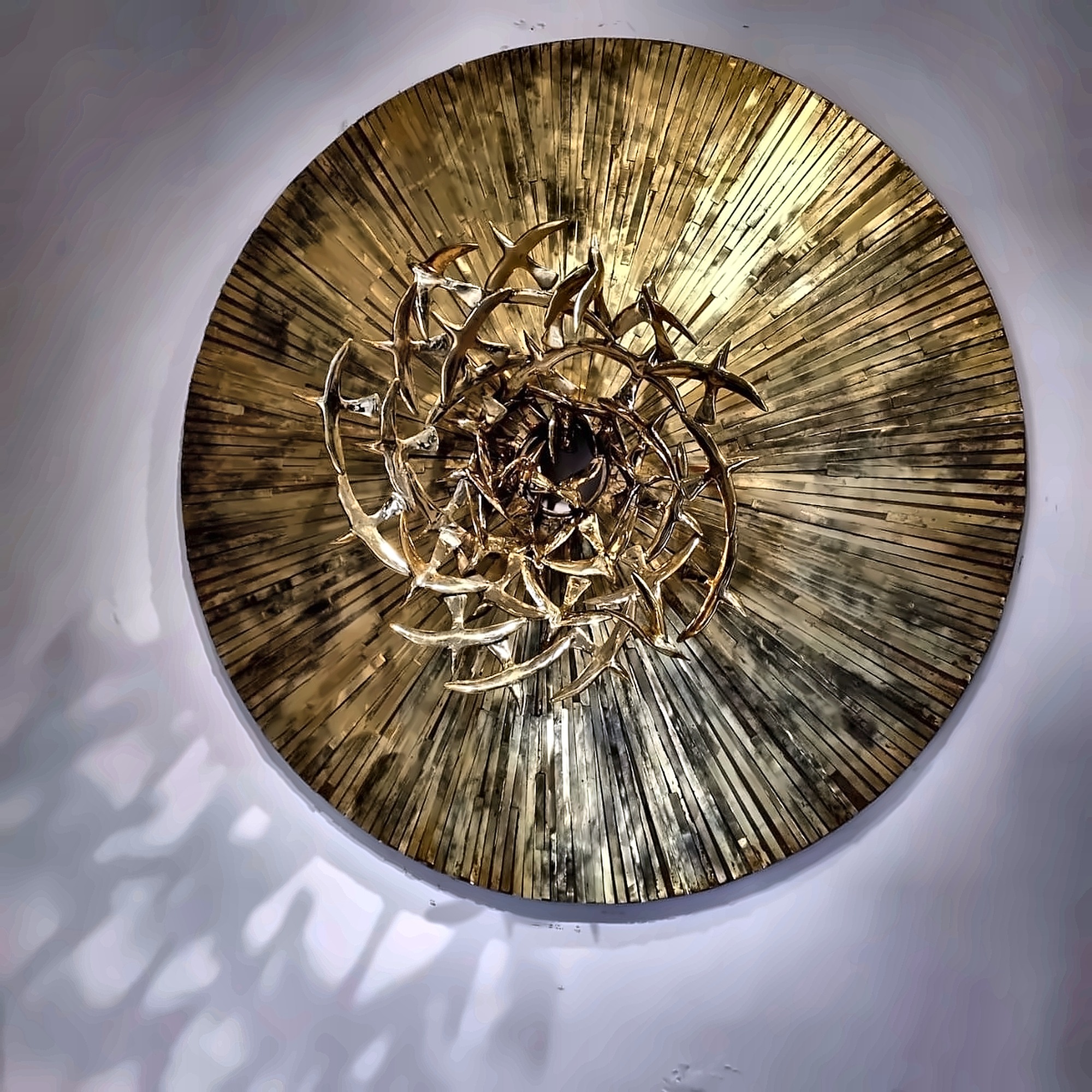 A circular brass work with birds turning toward a dark centre.