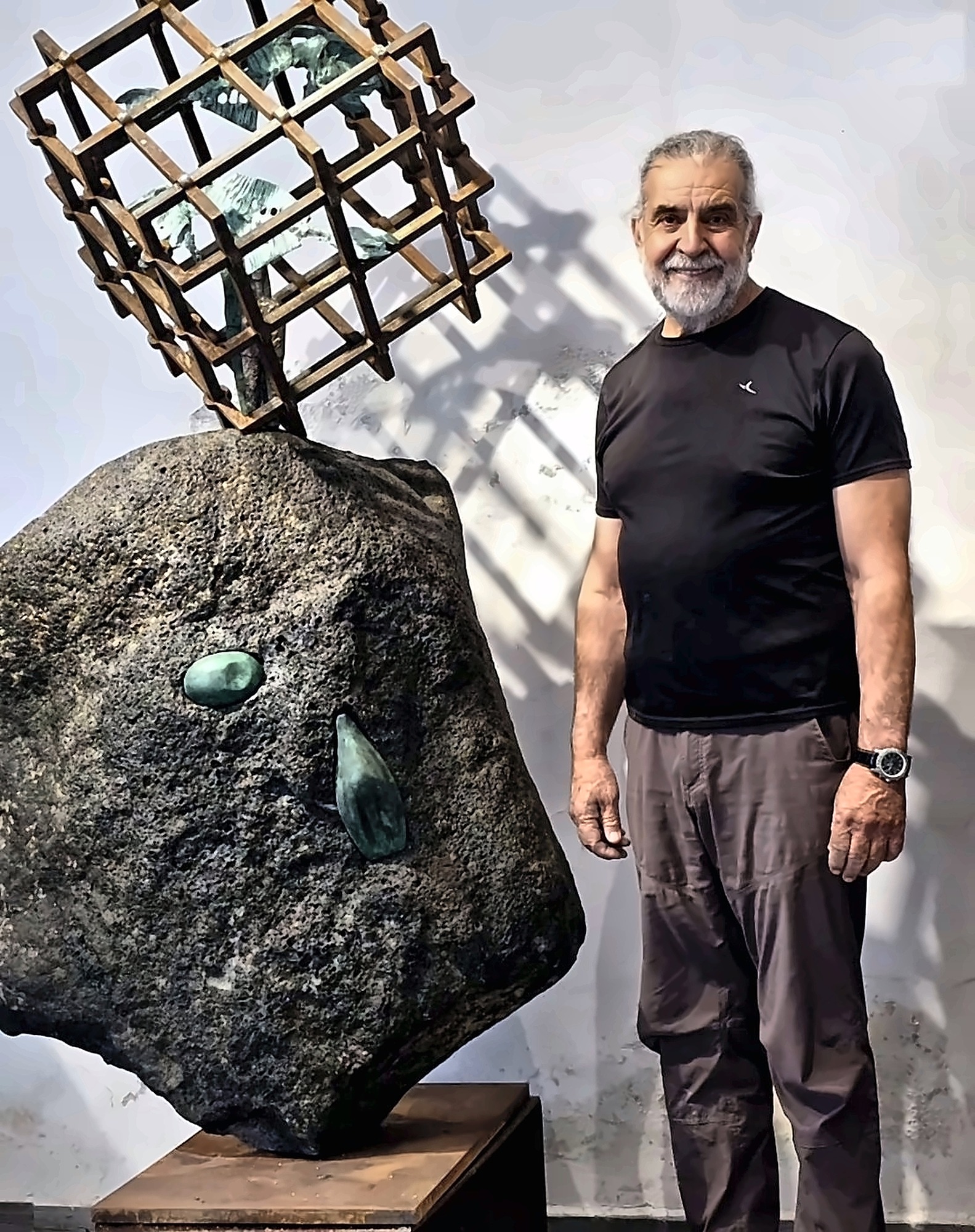A basalt boulder wrapped in a bronze cage with small birds inside.