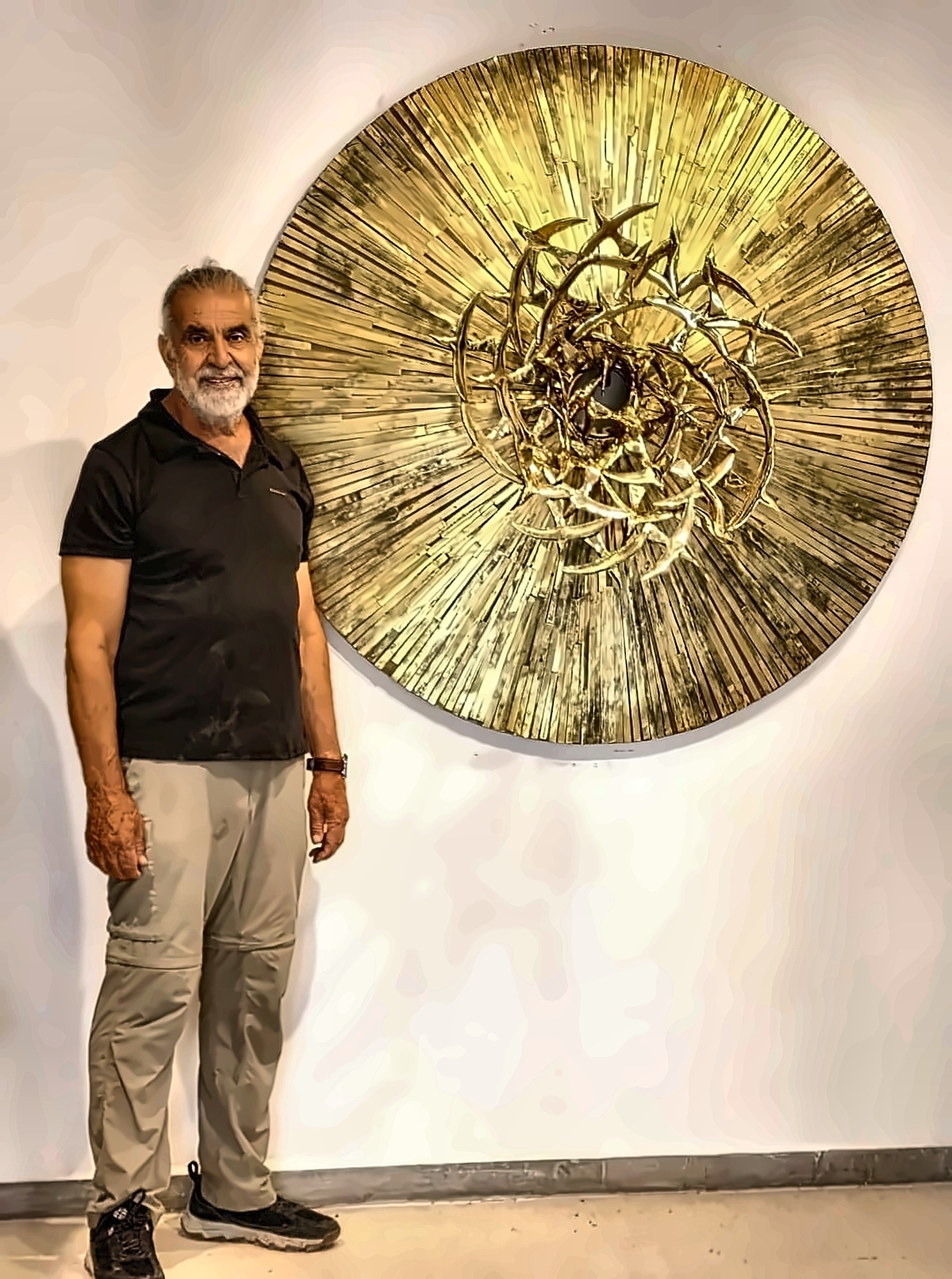 Hazem Al-Zubi standing beside the circular brass relief, which is roughly his own height.