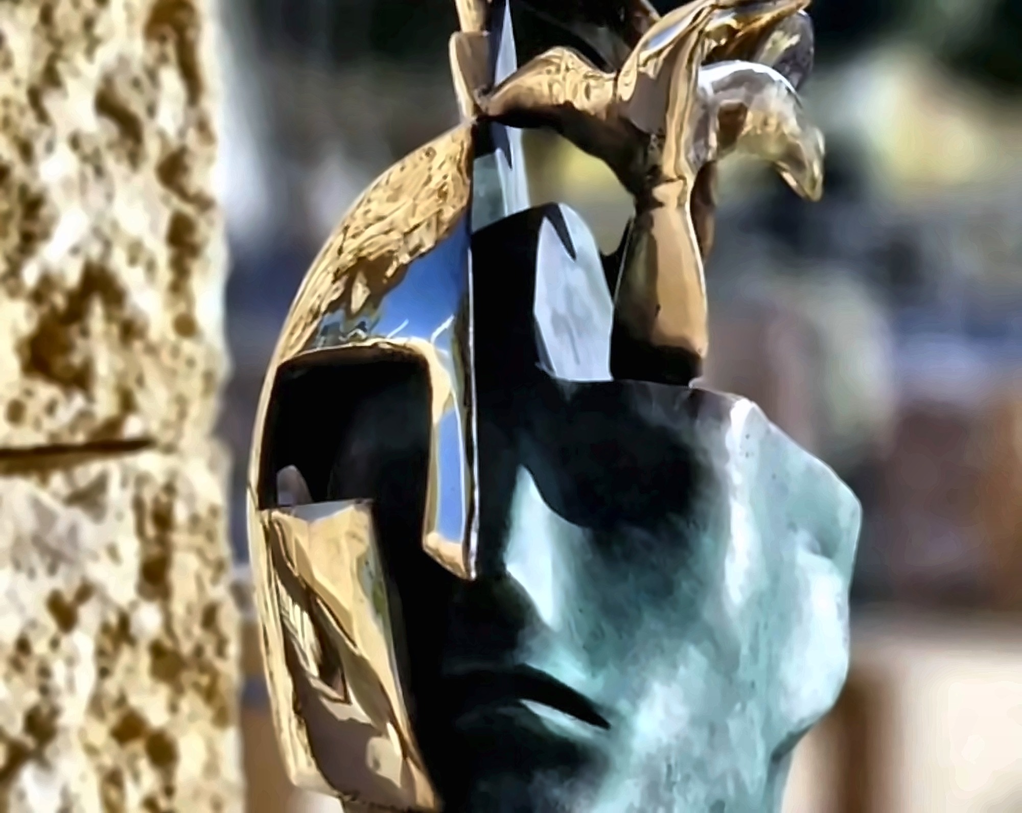 A glazed ceramic head form seen close, the surface pitted and warm.