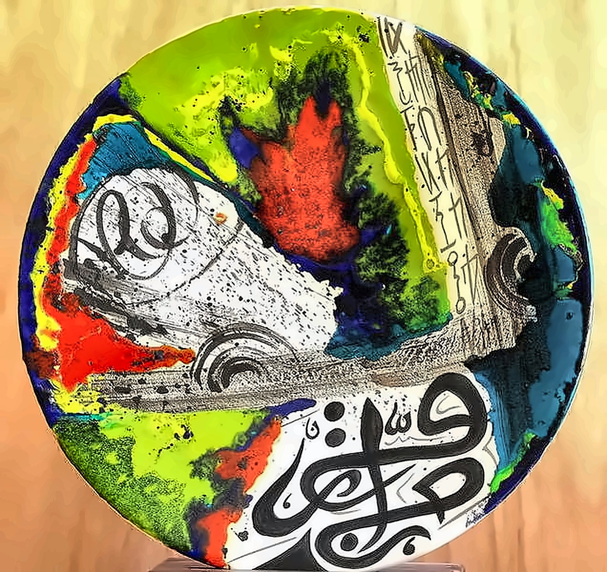 A plate where black calligraphy sits over poured red, green and blue that has run together.