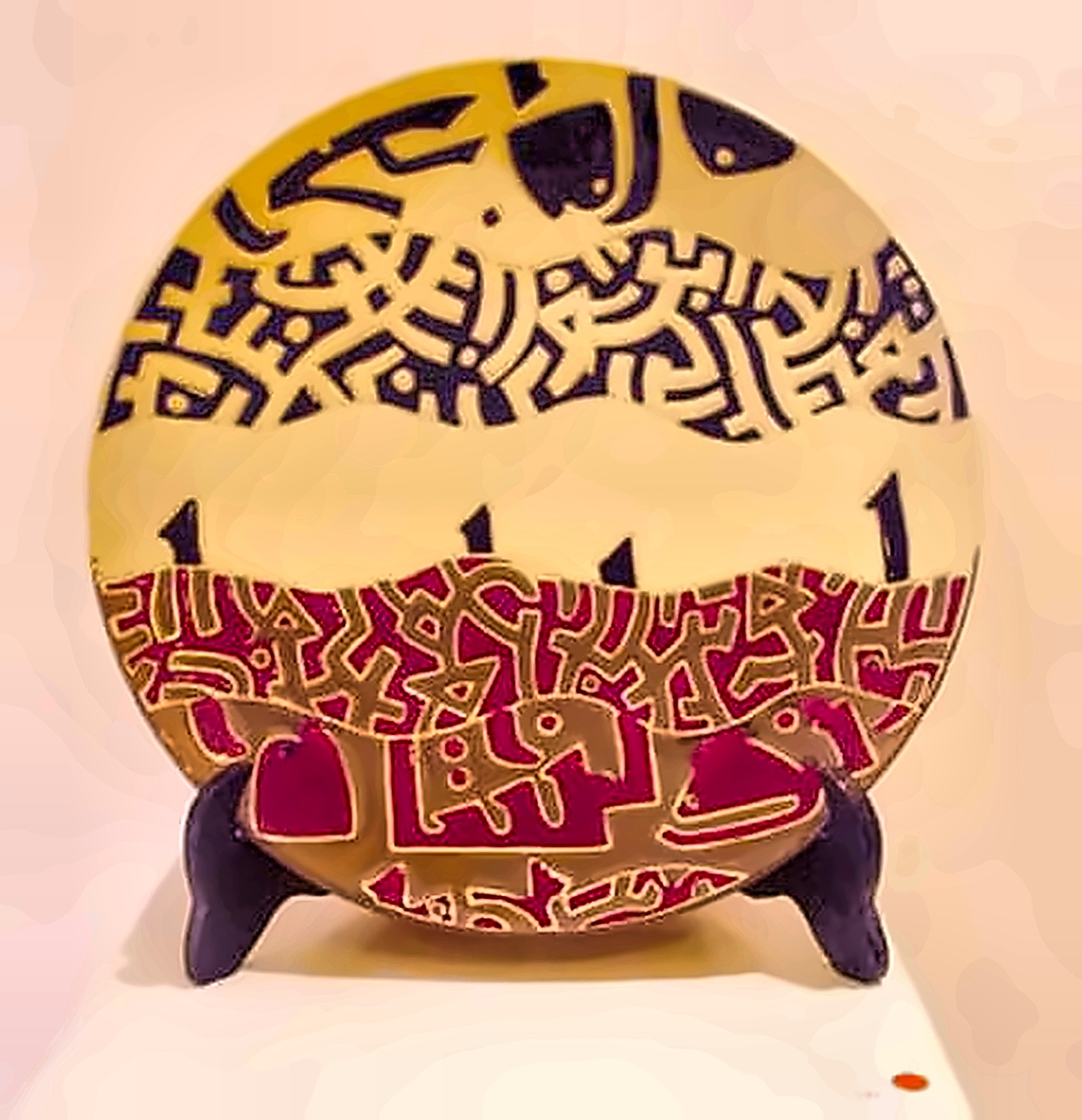 A plate divided between a yellow field of black interlace and a red field of pale animal figures.