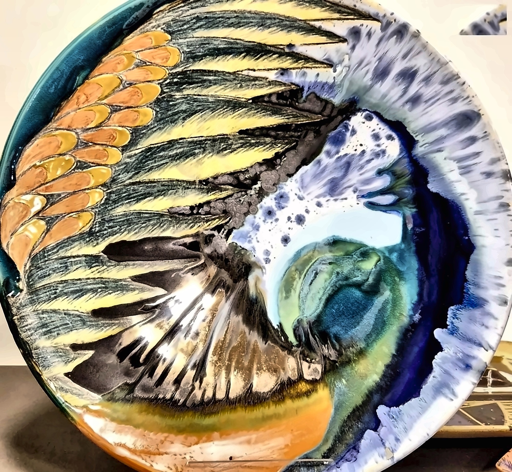 A ceramic plate with a winged form incised and glazed into it.