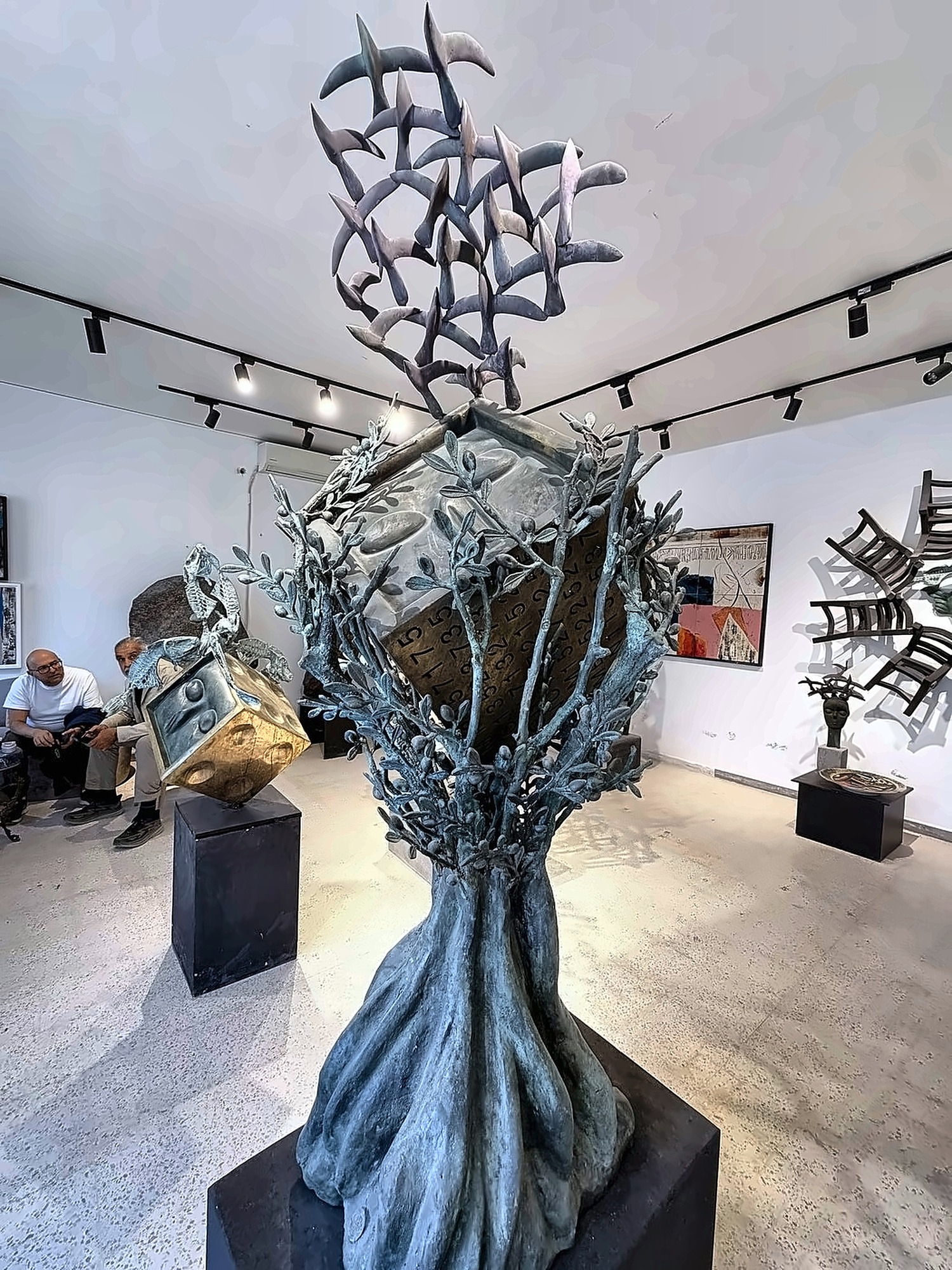 A bronze tree sculpture with birds lifting from its crown.