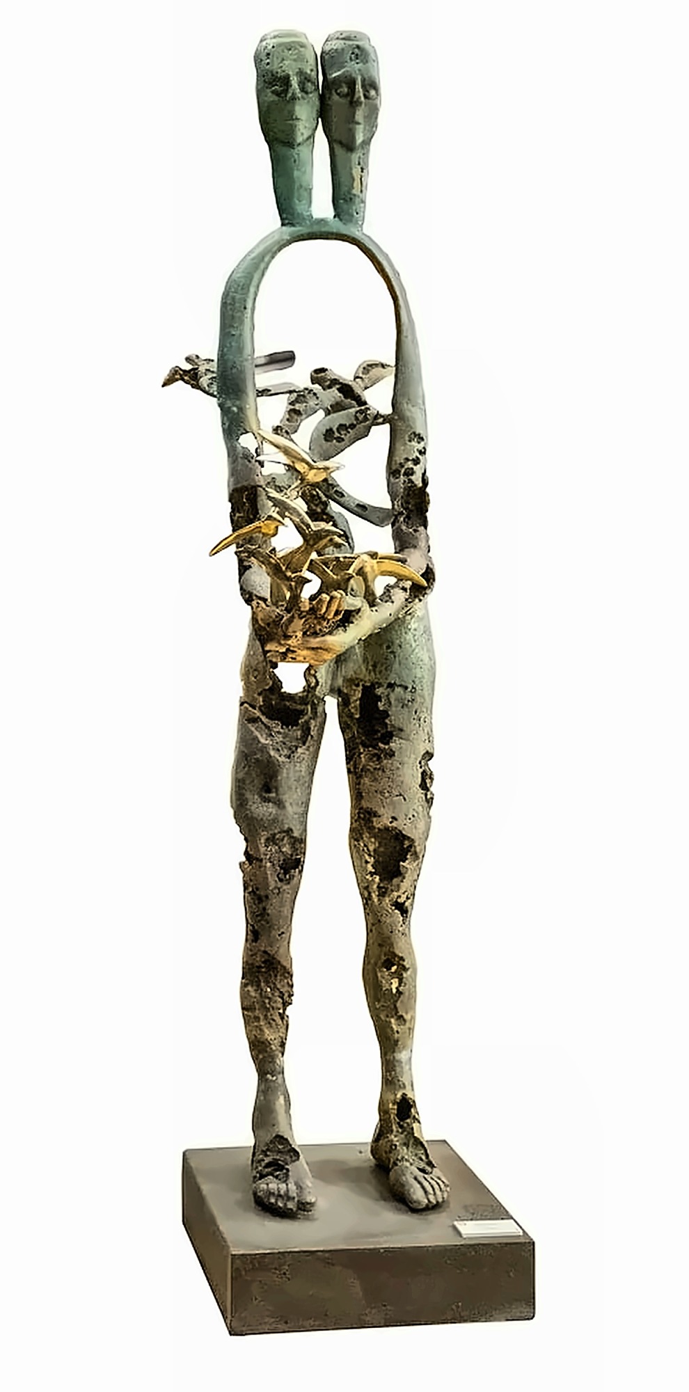 A tall bronze figure with two heads on one neck, its torso an open arch, holding a mass of gilded birds in both hands, the metal pitted and holed throughout.