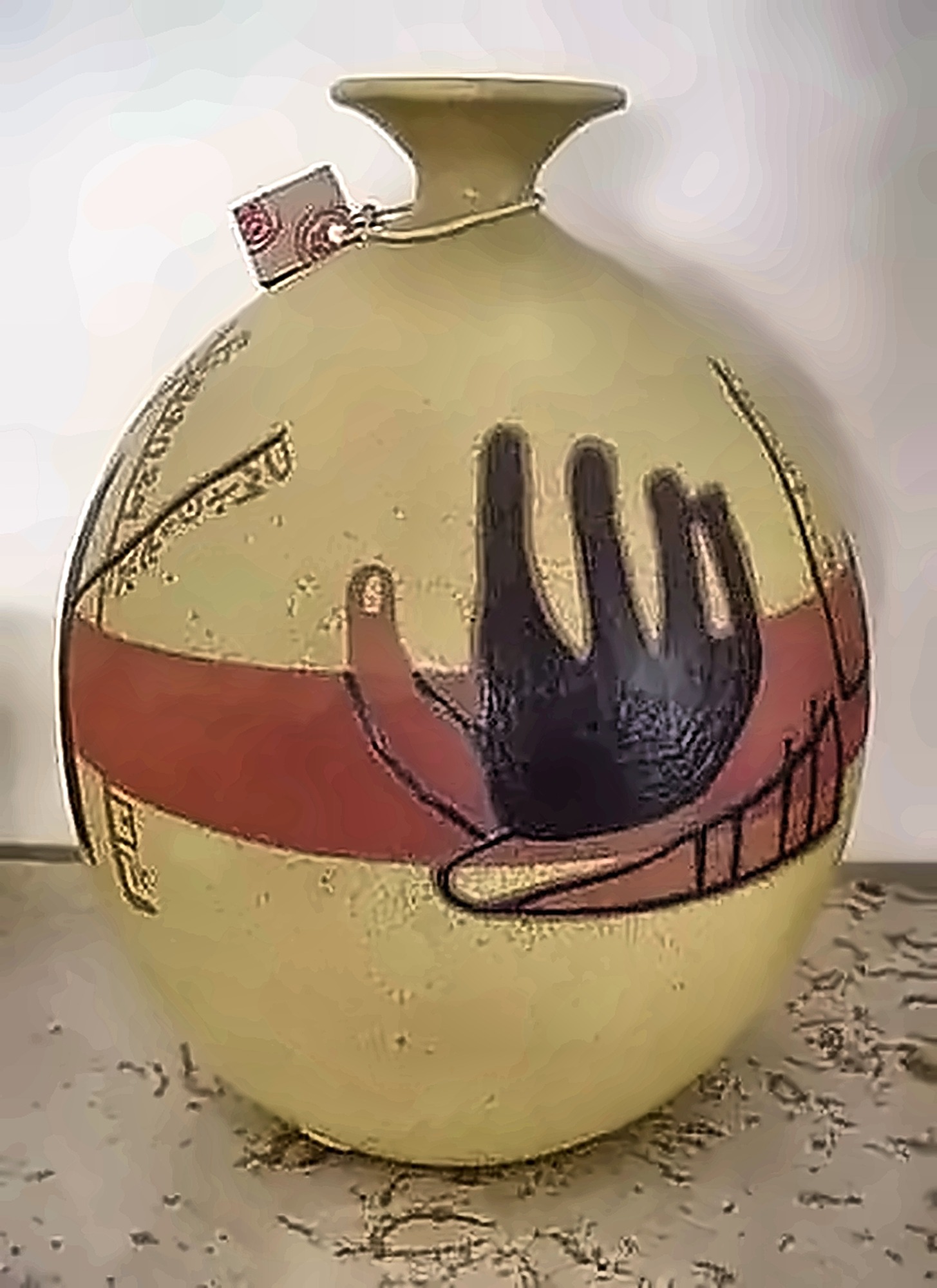 An ochre jar with a red band and a black hand laid across it.