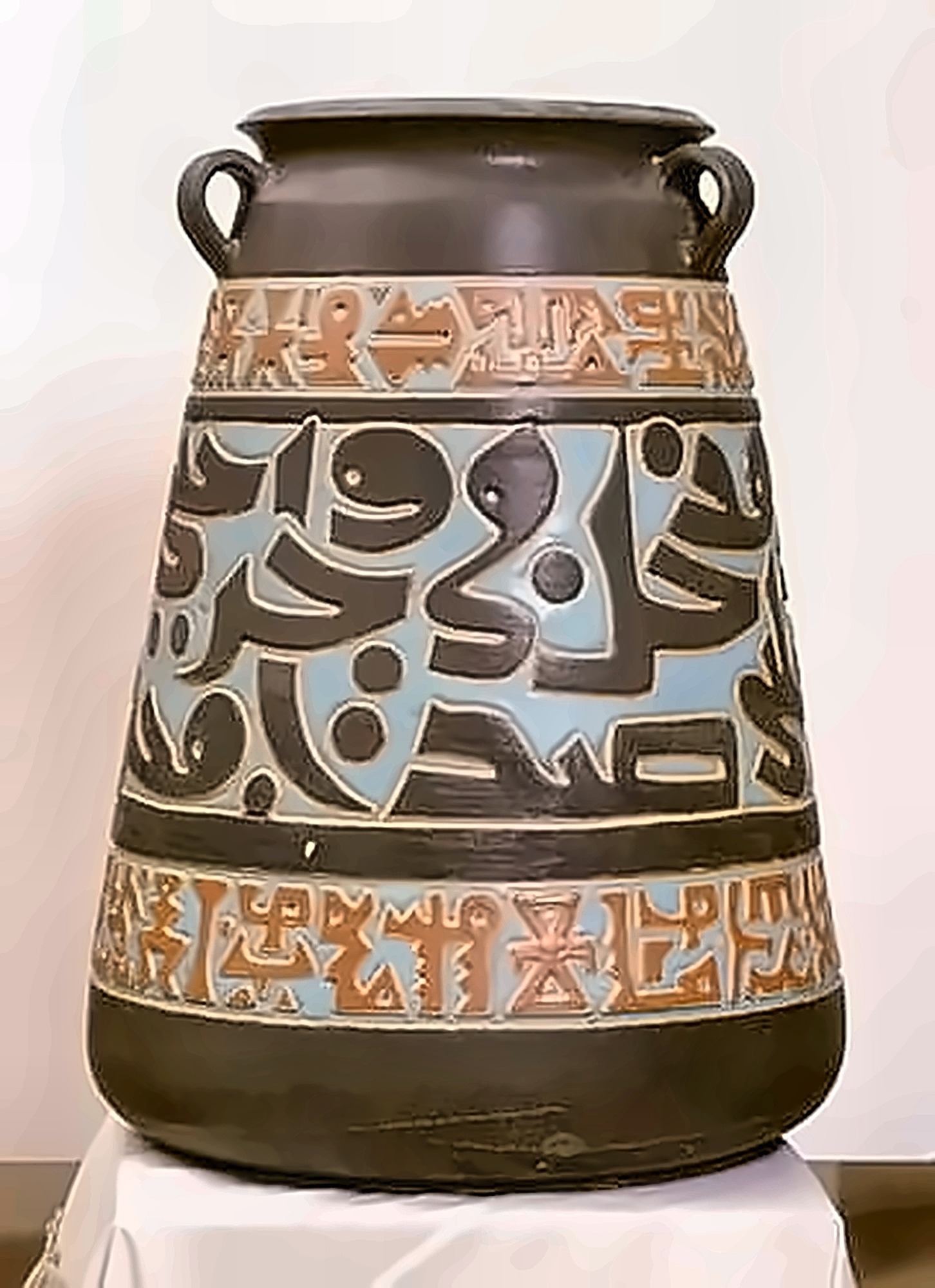 A large dark two-handled jar with three bands of incised script, the middle band pale blue, the outer bands terracotta.