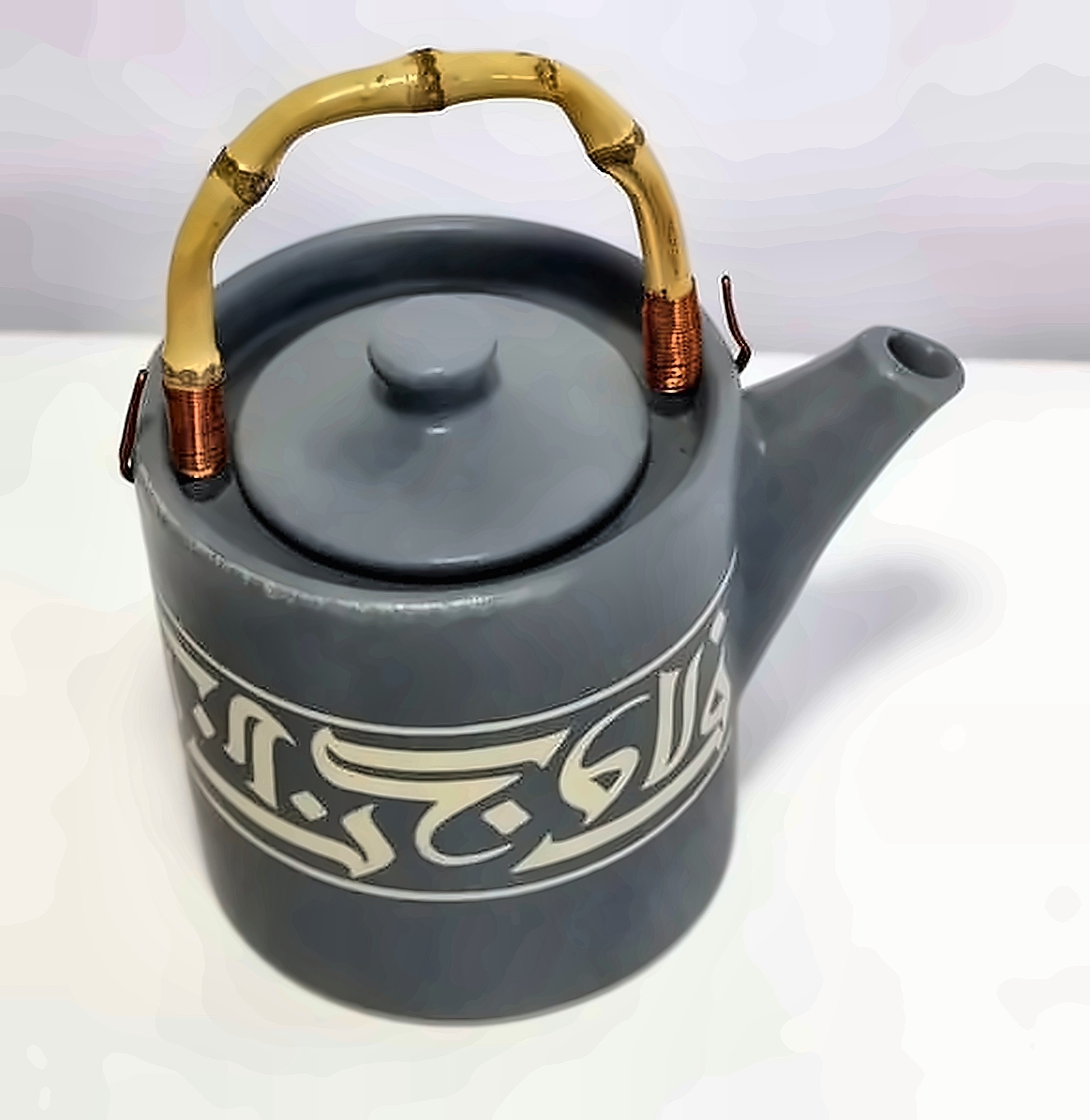 A grey teapot with a bamboo handle, a band of pale Kufic calligraphy round the body.