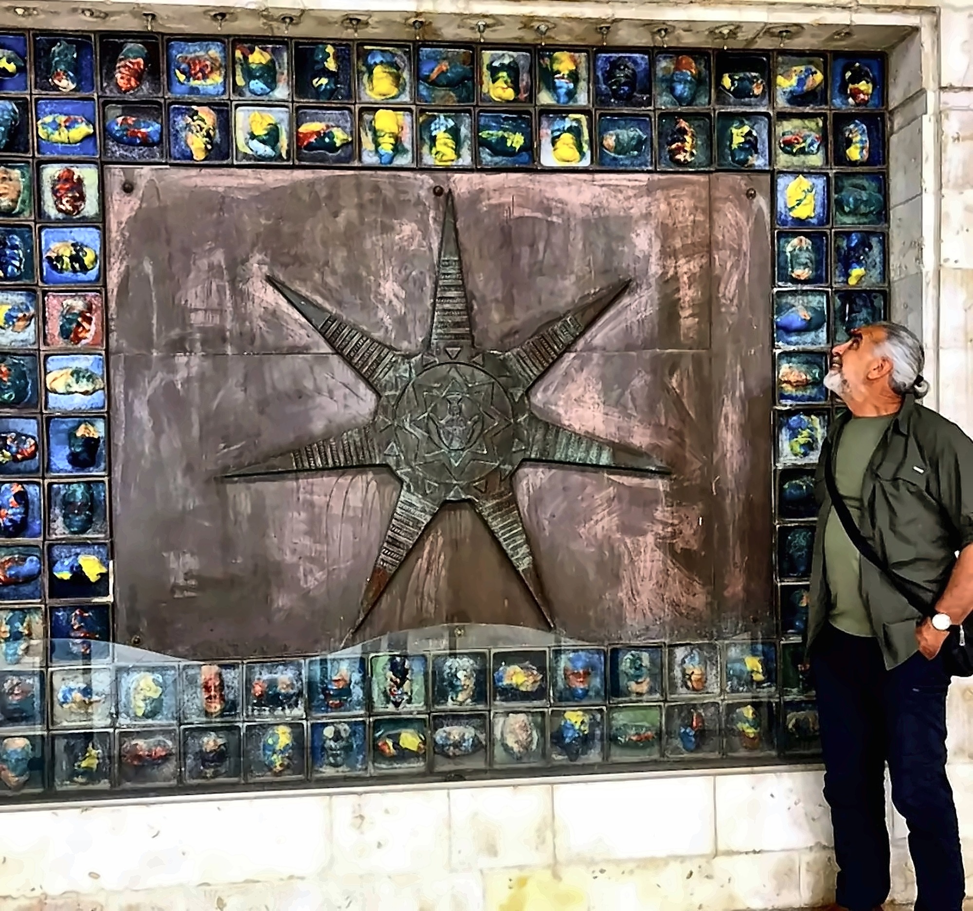 A large wall of ceramic tiles with a bronze star form at its centre.