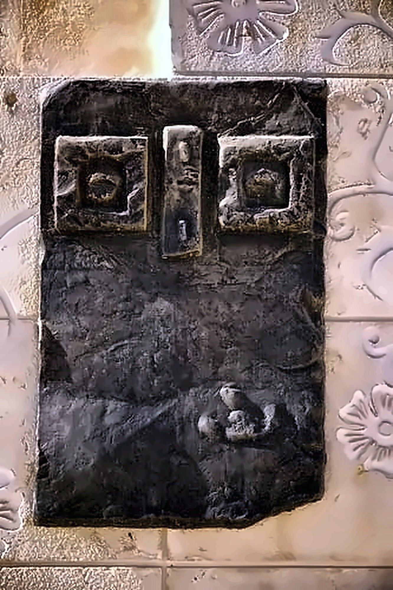 Close detail of a bronze face — the brow, the long nose and the lips catching light.